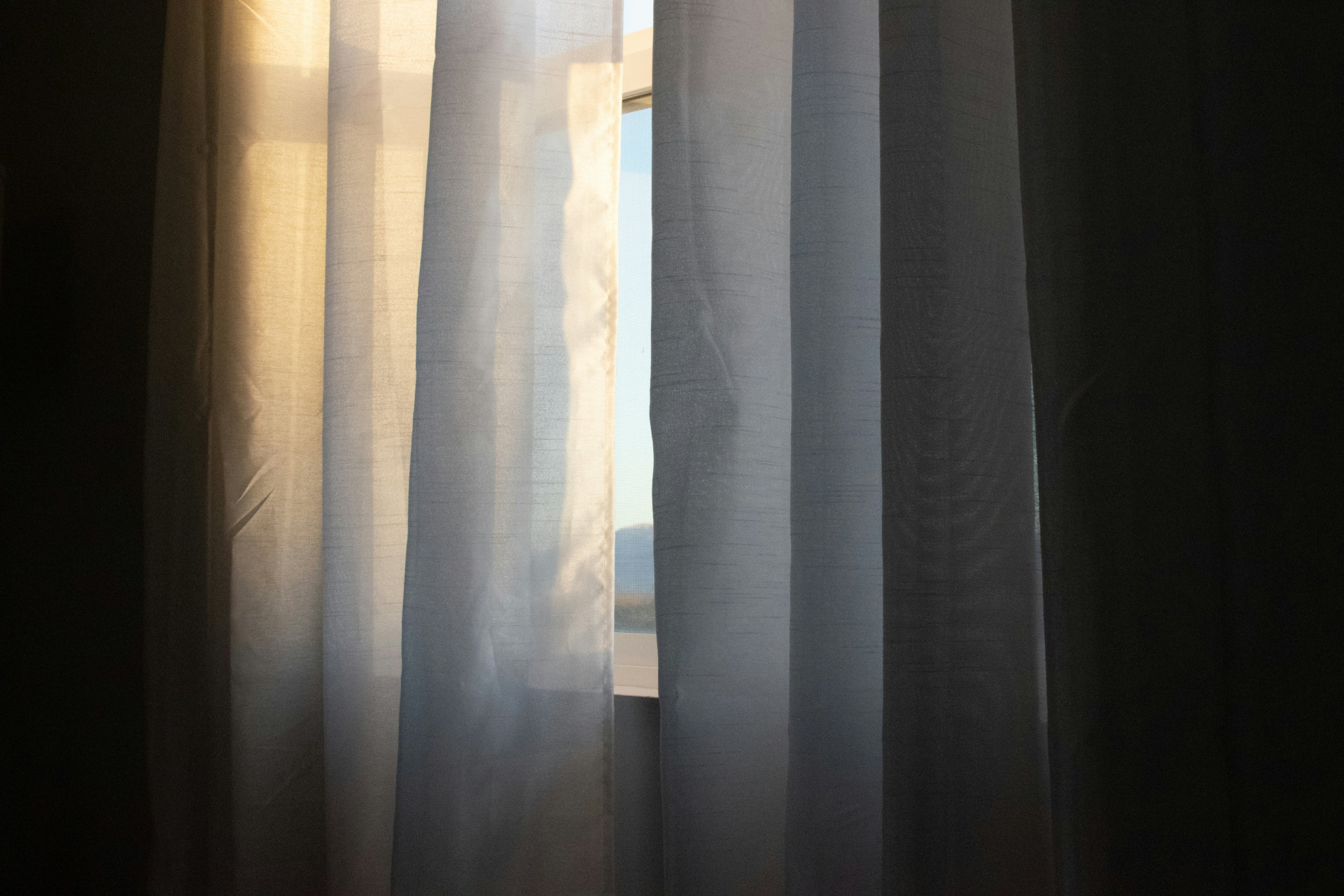 a close-up of a curtain with a window in the background